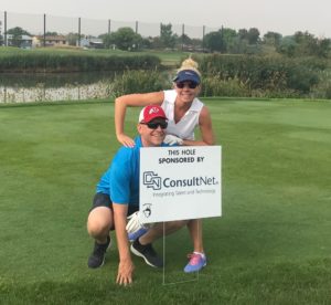 ConsultNet employees stand behind ConsultNet sponsorship sign at StoneBridge Golf Course, SLC