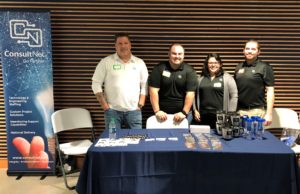 Team standing behind table and ConsultNet sign at Google DevFest 2018