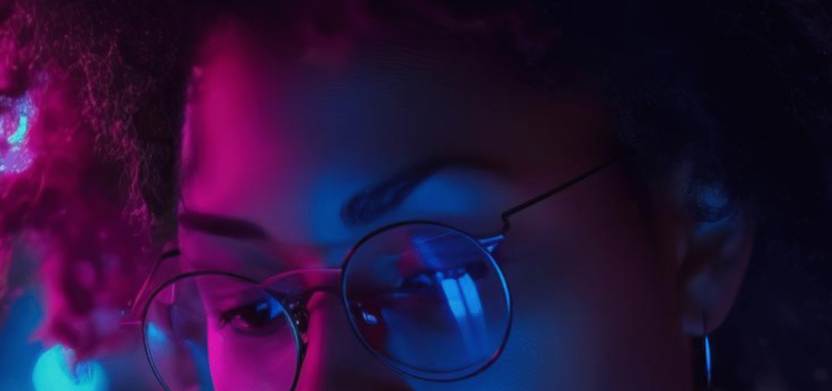 Girl in purple and blue shadows looking at computer