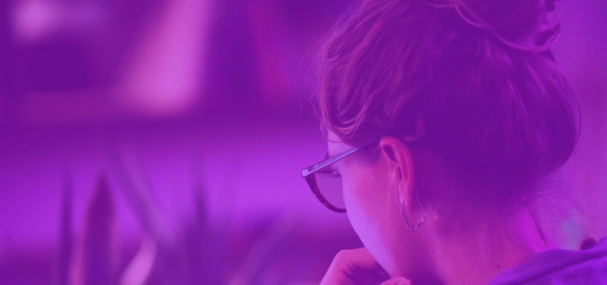 woman looking at a laptop from behind with purple overlay